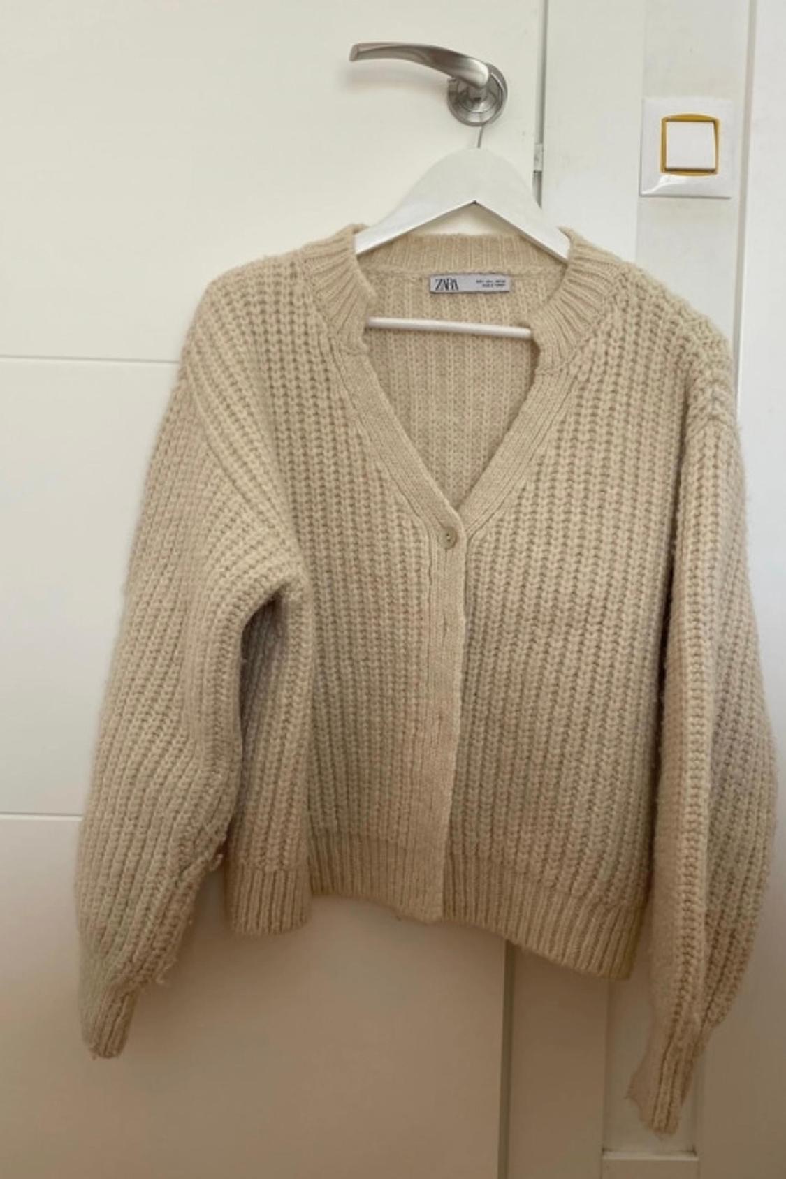 Front view of a chunky knit beige cardigan with buttons.
