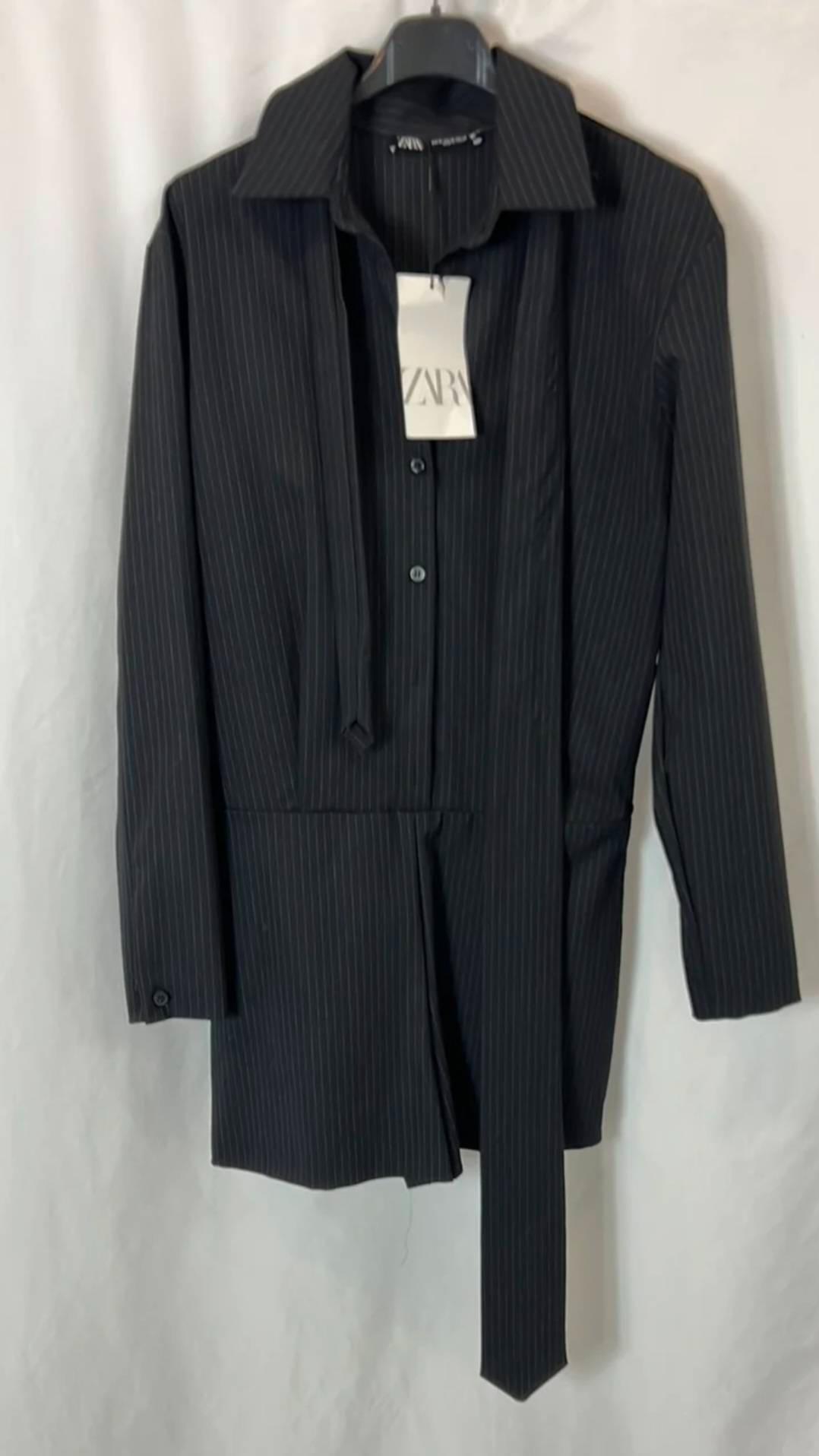 Black long-sleeved shirt with white stripes and a hanging strap, on a hanger against a white background. Label with the text ZARA.