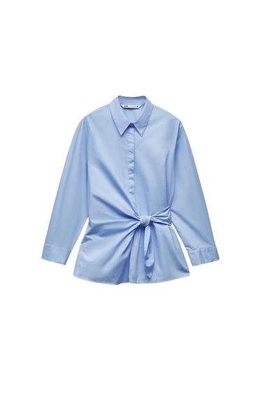 Light blue long-sleeved collared shirt with front fastening and a knot detail at the waist on a white background. ZARA label.