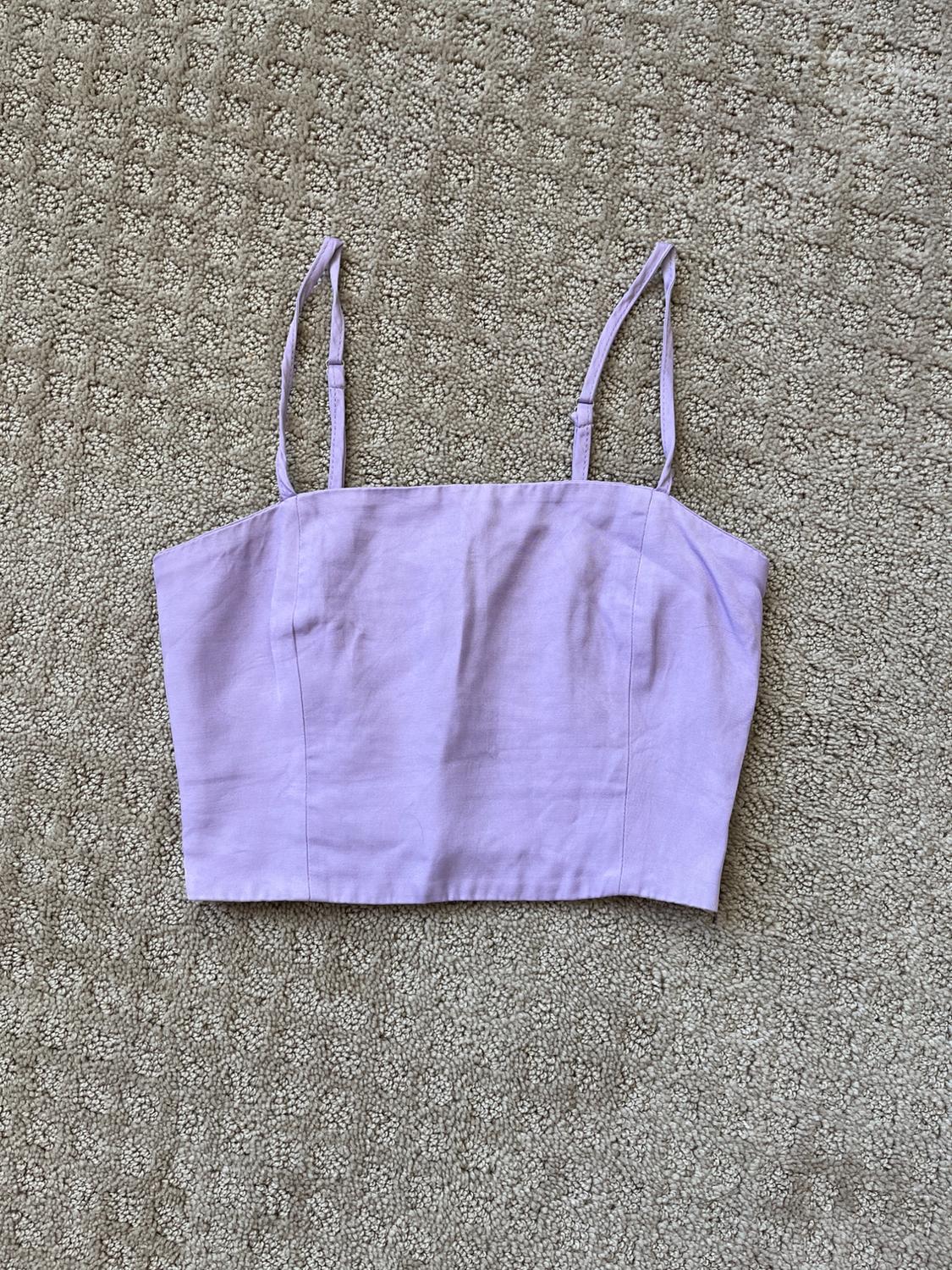 Lilac crop top with adjustable thin straps, on a textured beige rug.