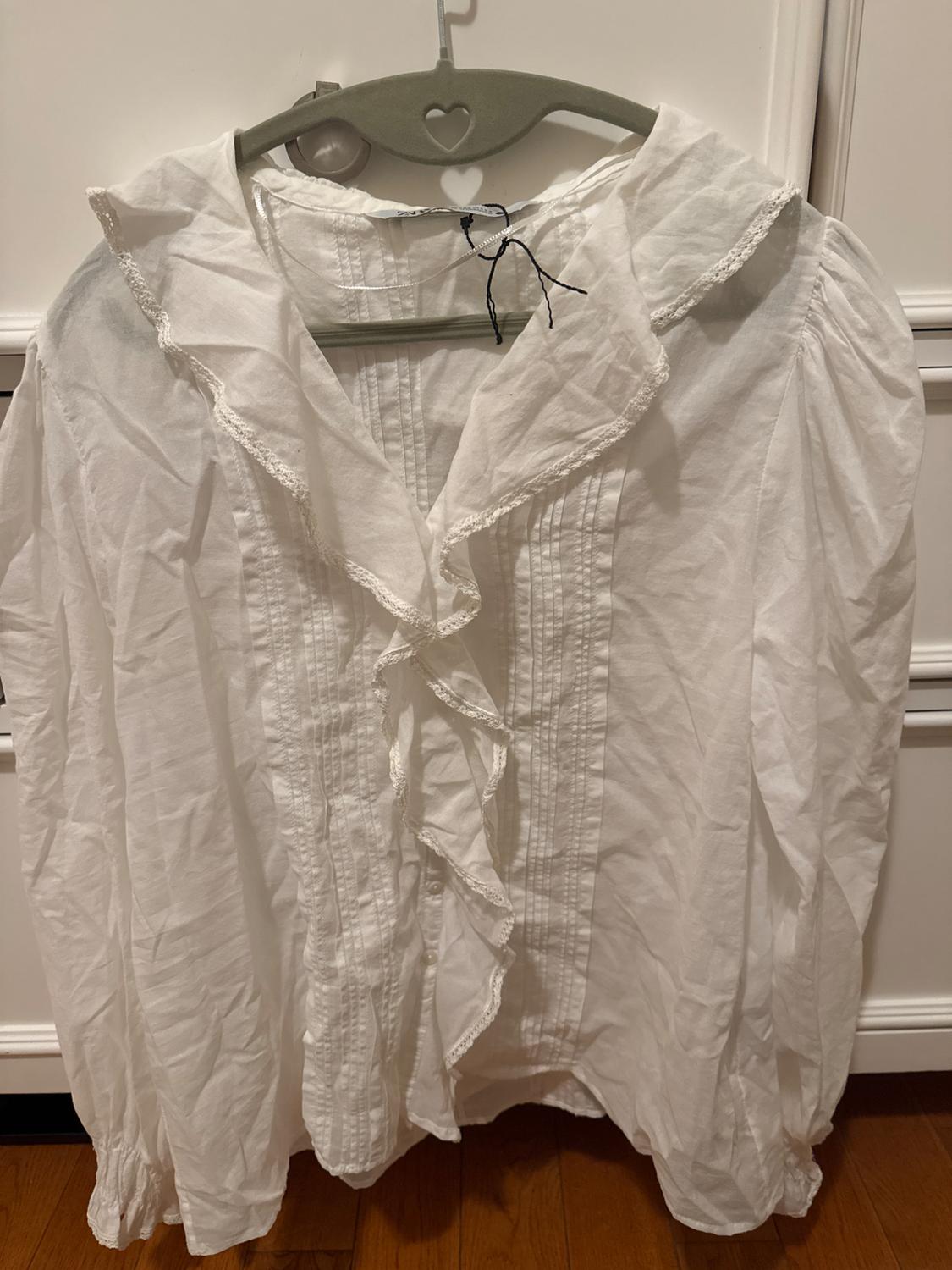 Front view of white blouse with ruffles and lace collar.