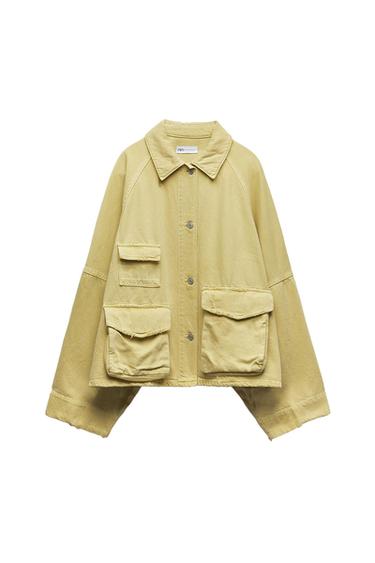 Long-sleeved beige jacket with large pockets and front buttons. White background. Visible label on the collar.