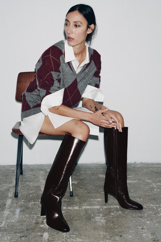 Sada vysokých bordó červených kozaček se širokým podpatkem, s bočním zipem, kombinovaná se svetrem s kosočtvercovým vzorem a bílou košilí.