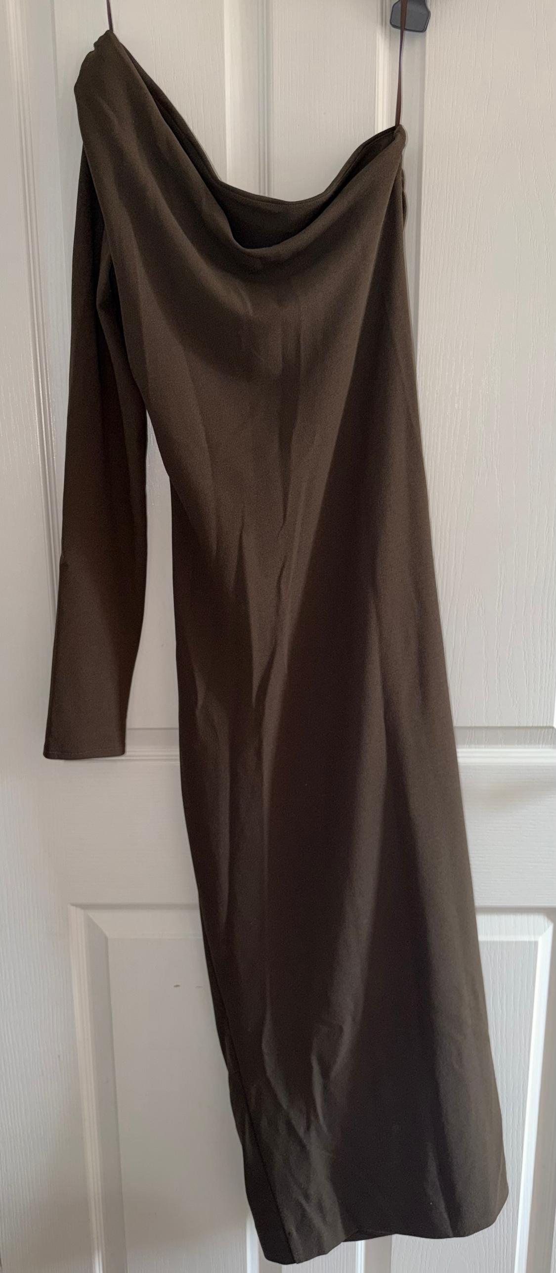 Brown one-shoulder dress hanging on a white door. Smooth, elegant drape to the fabric.