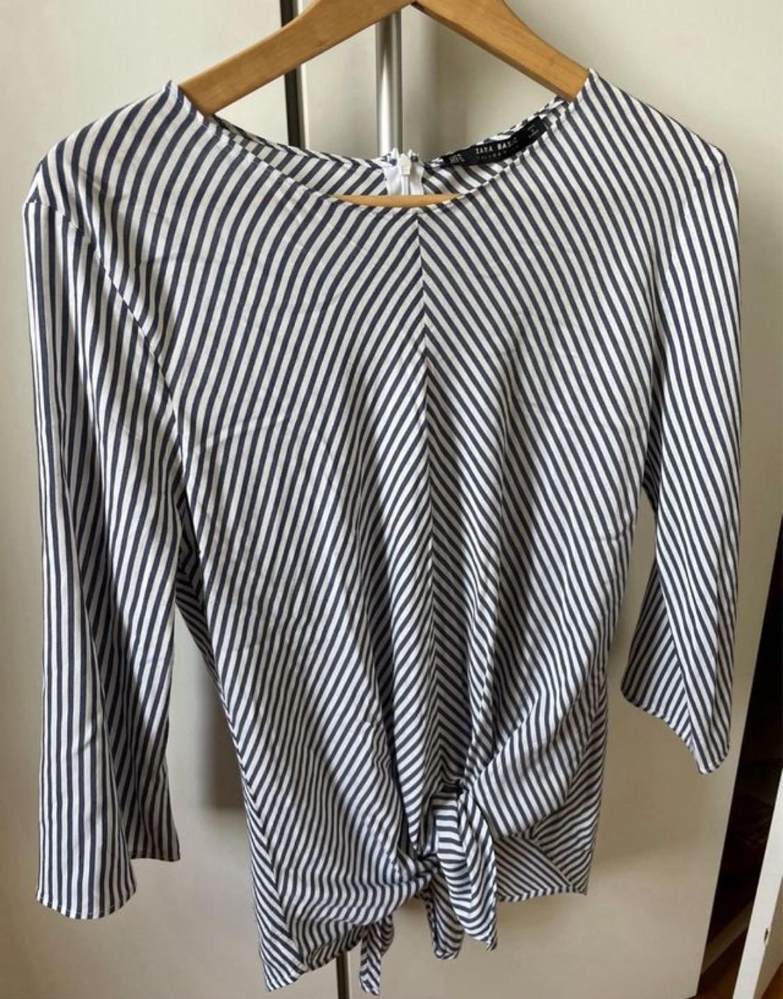 Front view of a black and white striped blouse with a tie waist and long sleeves.