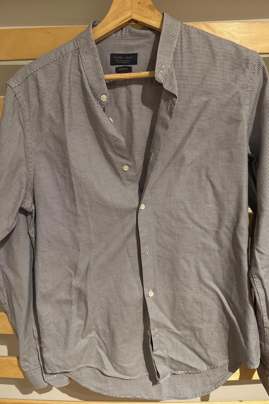 Front view of a small checked black and white shirt with white buttons and an open collar.