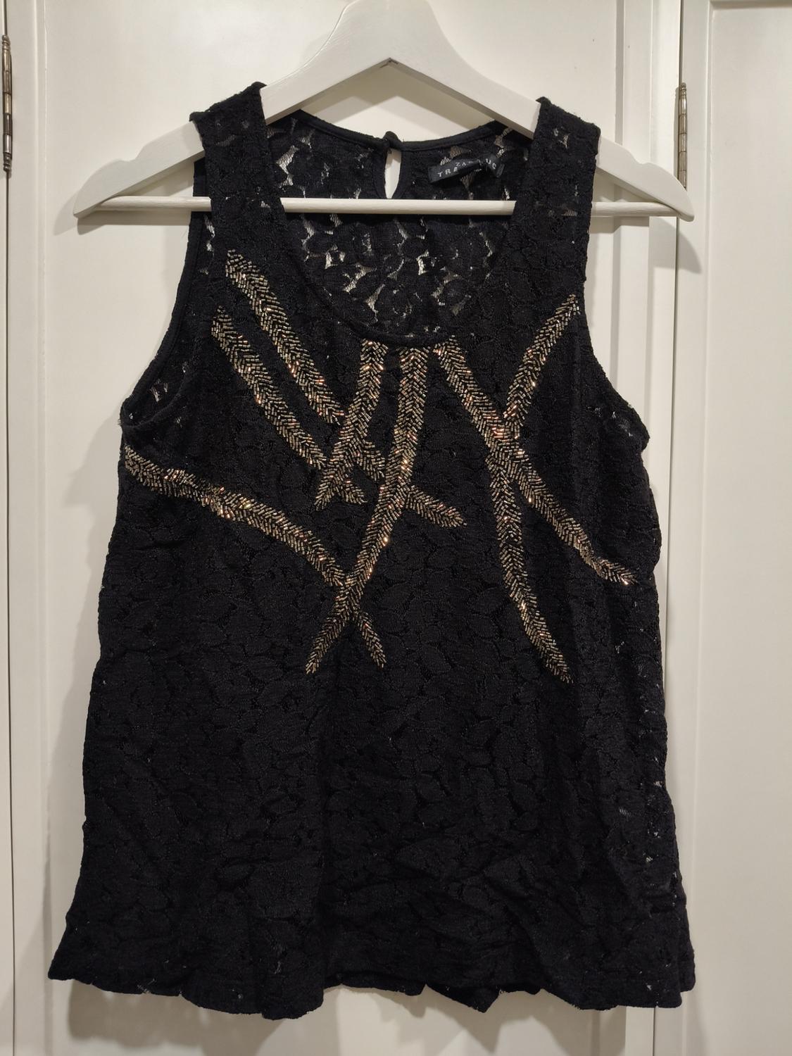 Front view of a black blouse with lace and gold geometric details.
