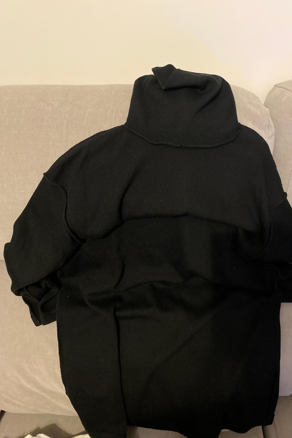 Rear view of a black polo neck jumper with long sleeves.
