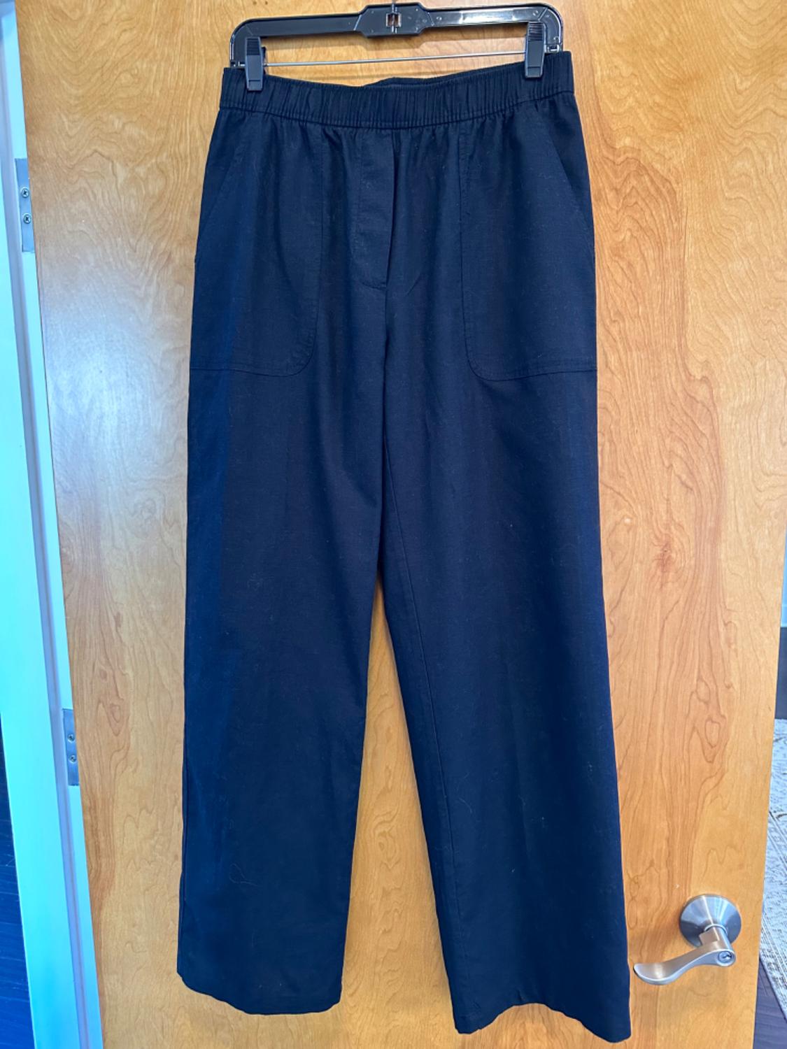 Front view of black trousers with front pockets and an elasticated waistband.
