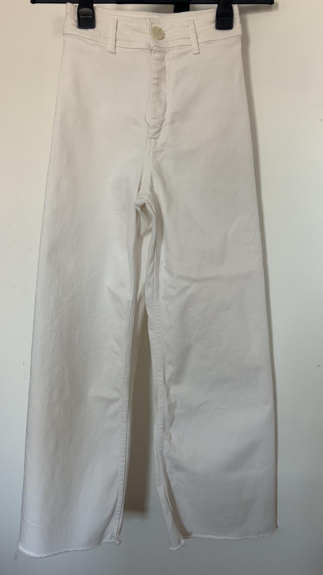 White denim trousers hung on a black hanger, with frayed hem and visible button at the top.