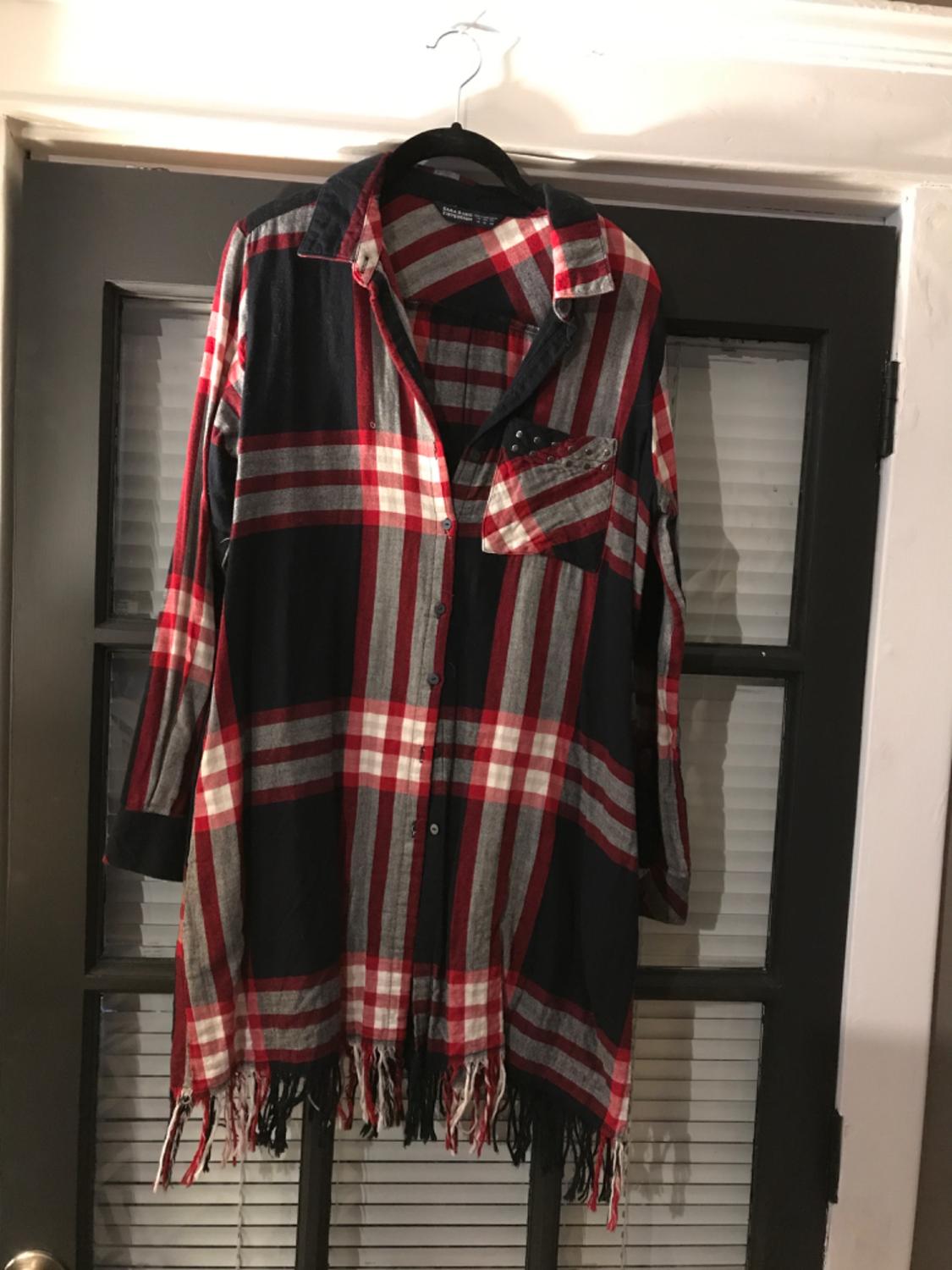 Front view of a red and black checked shirt with fringing on the hem and a front pocket.