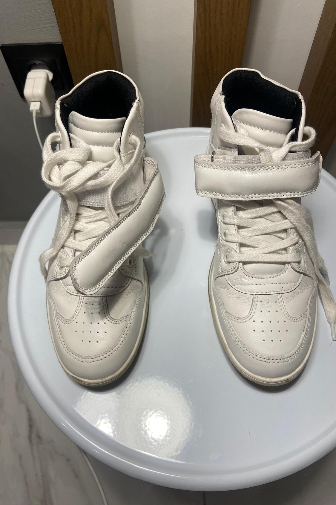 Top view of white high-top trainers with laces and adjustable straps.