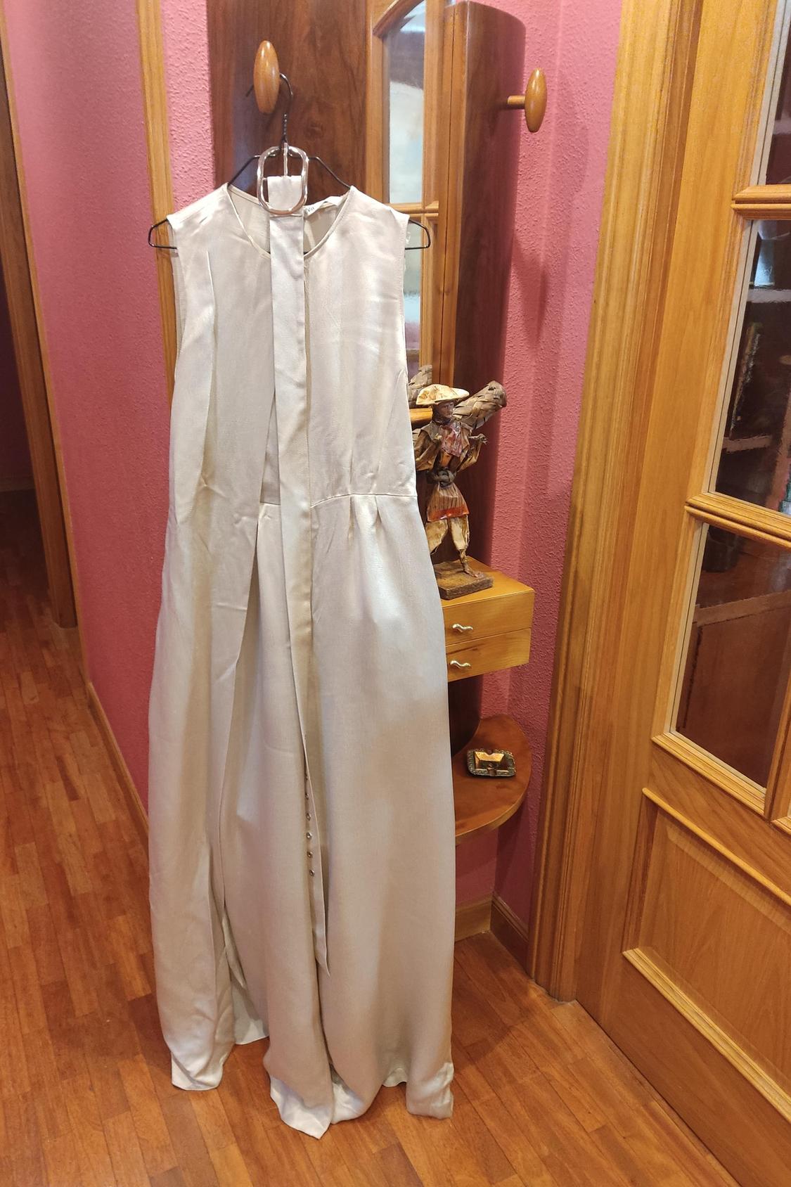 Front view of long sleeveless beige dress hanging on a hanger.