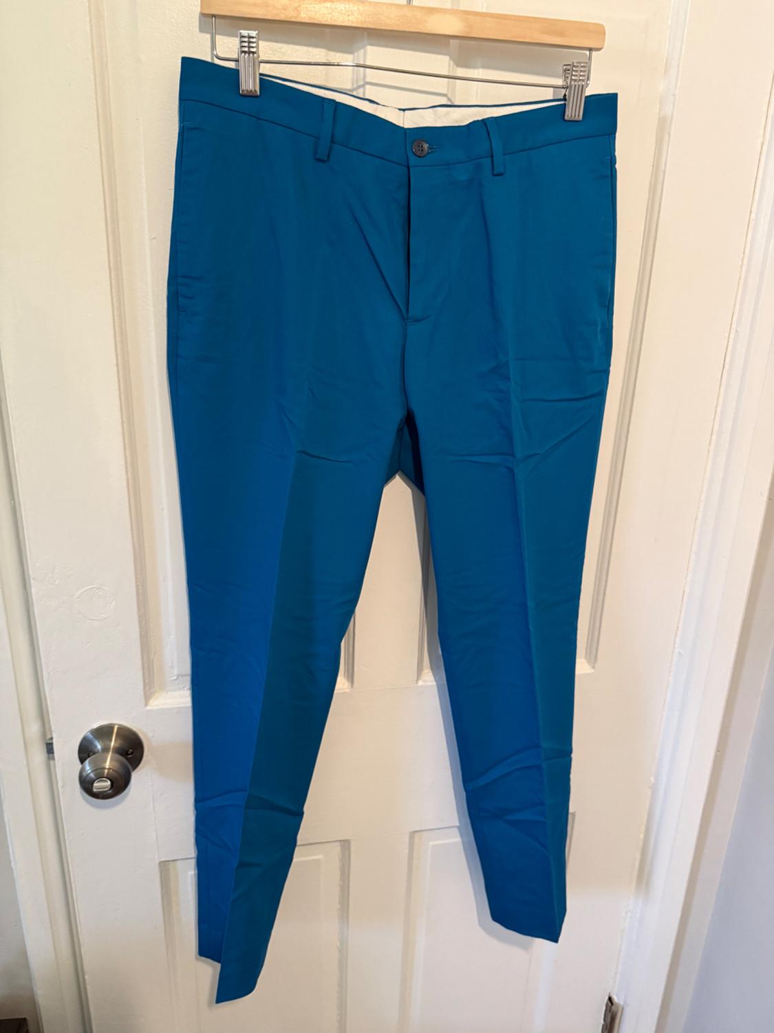 Front view of blue trousers with side pockets and a front button.