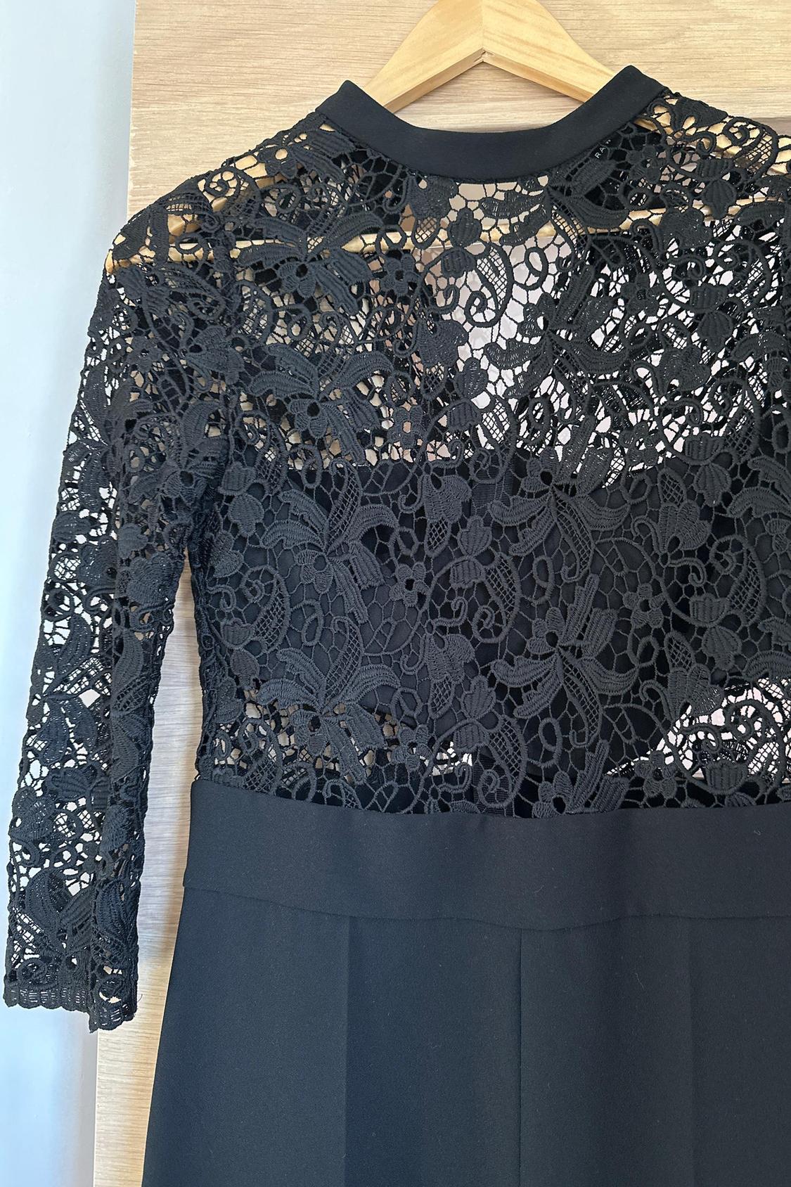 Black floral lace detail on the bodice of a dress with long sleeves.