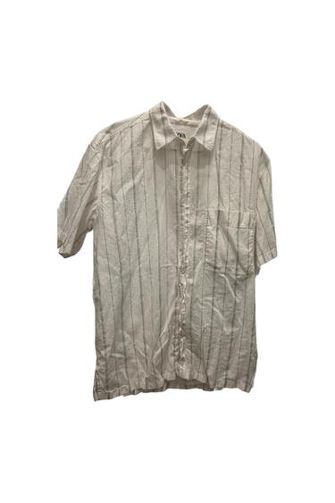 Short-sleeve Ecru shirt with dark vertical stripes, buttons, and a chest pocket against a white background. ZARA text.