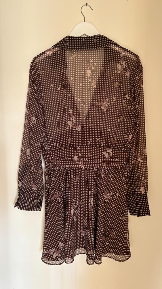 Brown chiffon blouse with a check and pink floral print, hanging on a white hanger against a beige background.