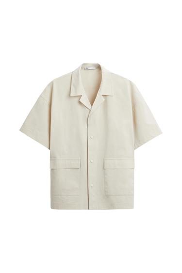 Front view of a beige shirt with an open collar and large front pockets.