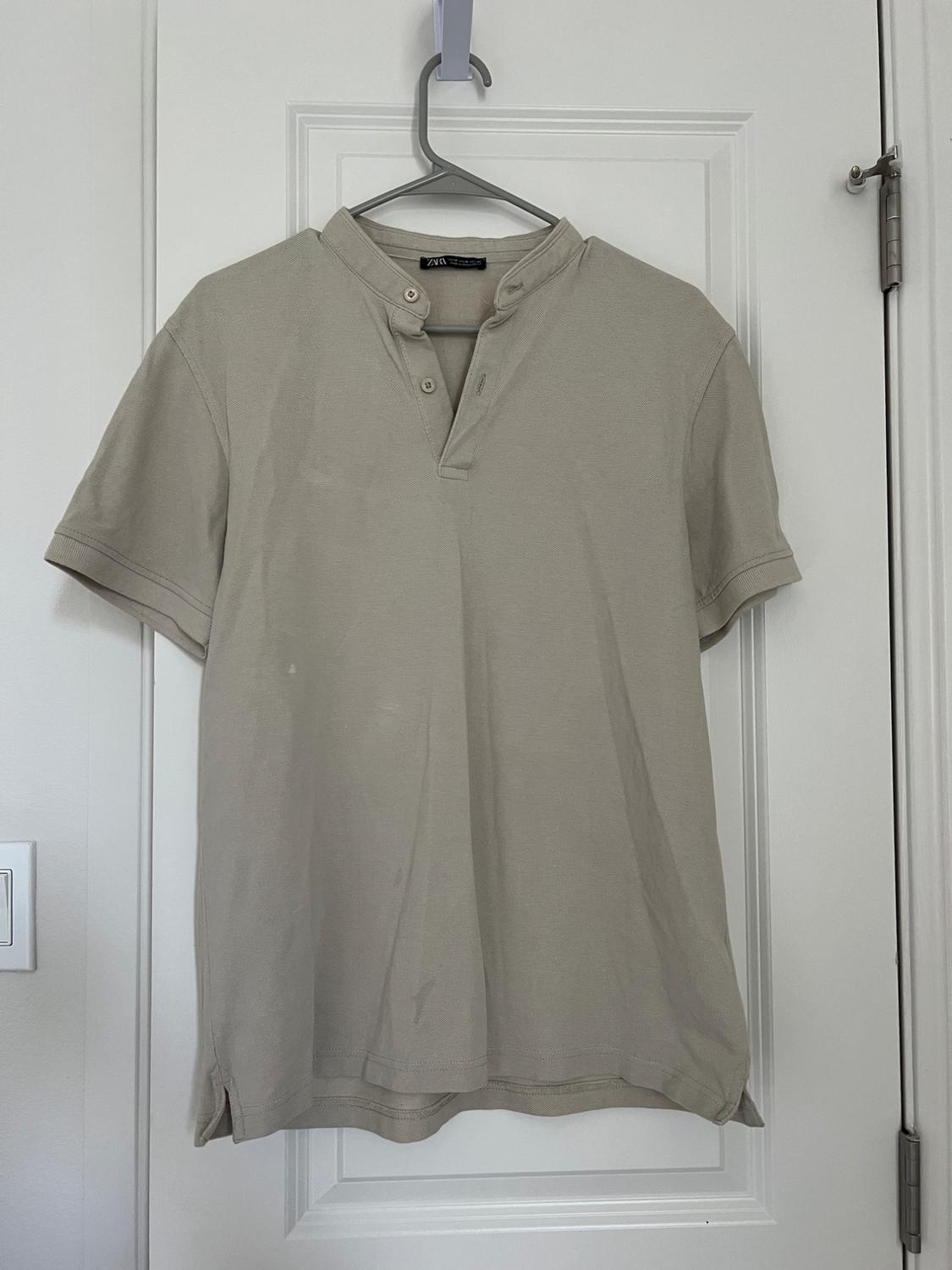 Front view of a beige t-shirt with a button-down collar and short sleeves.