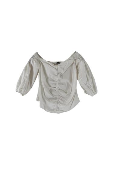 Front view of a white blouse with puffed sleeves and a boat neckline.