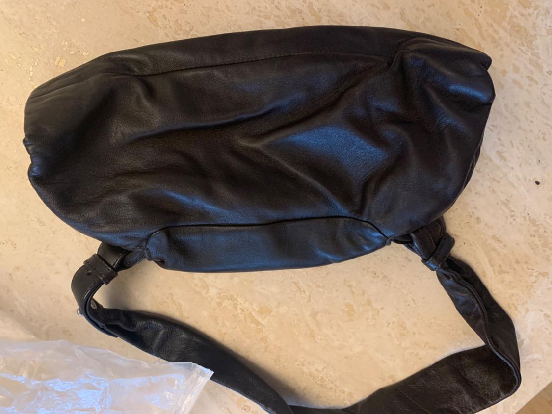 Top view of a black bag with an adjustable strap and visible clasp.