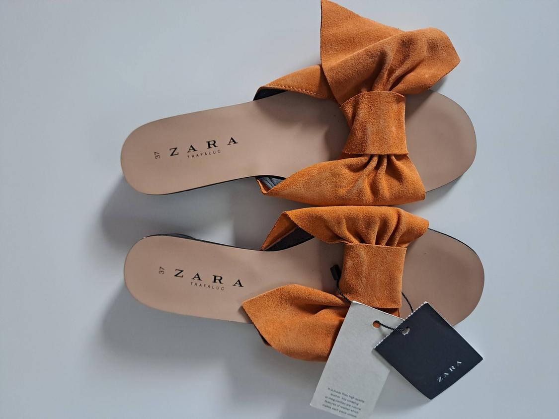 Mustard flat sandals with bow and labels on a light background. Text: 37 ZARA TRAFALUC, ZARA.