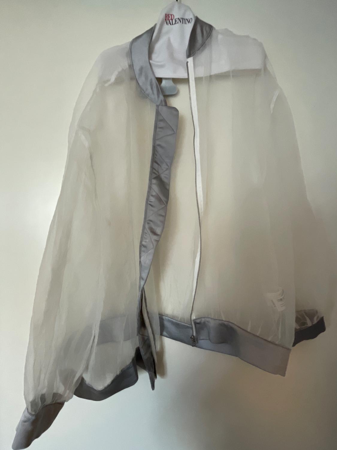 Sheer jacket with grey trim hanging on a white hanger with the text "RED VALENTINO" at the top.