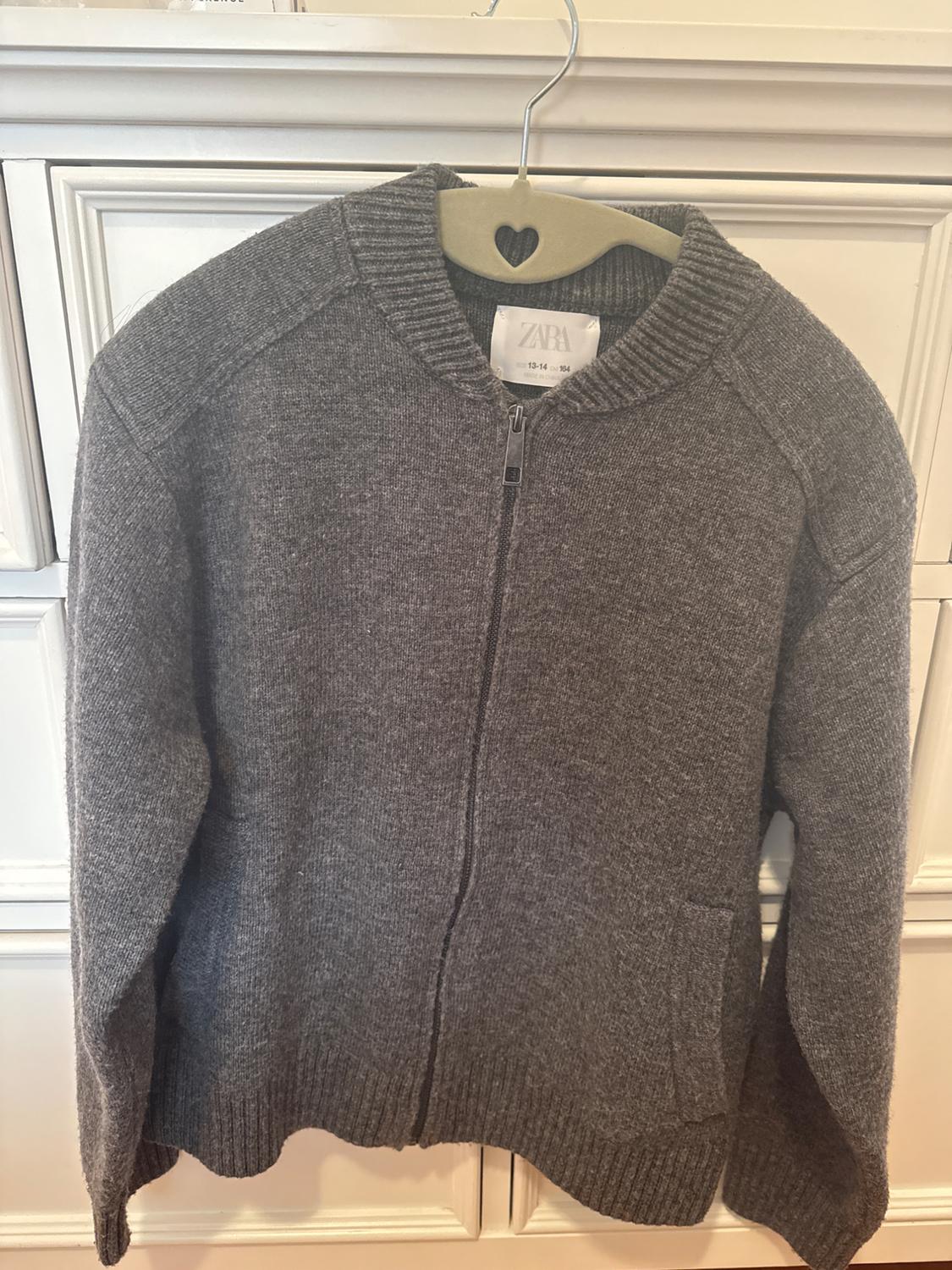 Front view of a gray jacket with a zipper and side pockets.