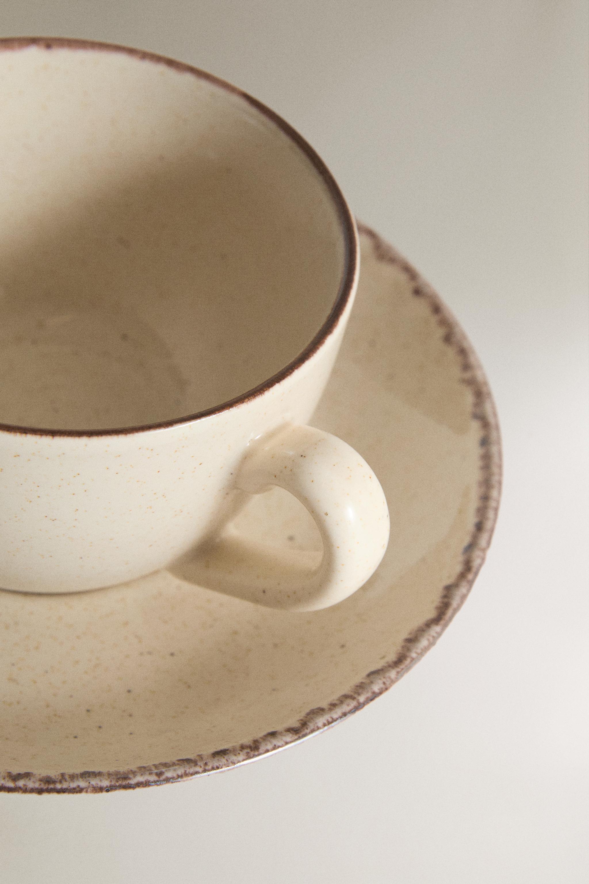 STONEWARE TEACUP AND SAUCER WITH DISTRESSED RIM