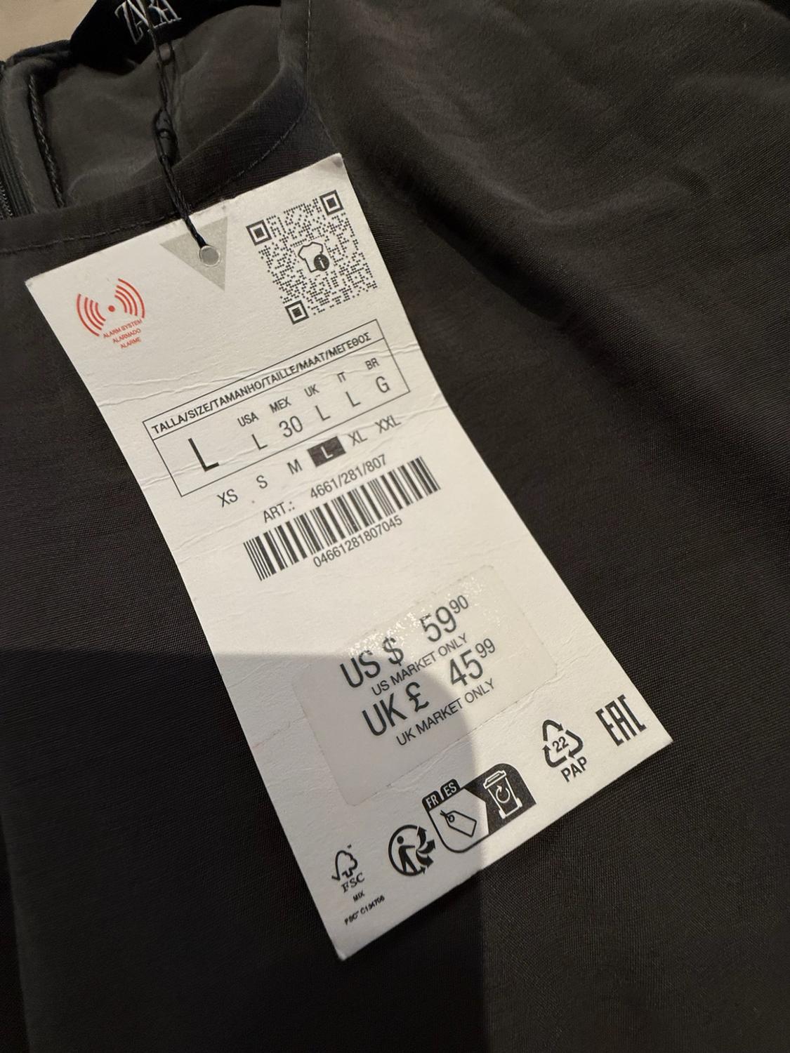 Label on dark fabric. Text: ALARM SYSTEM, SIZE L, XS S M L XL XXL, ART.: 4661/281/807, US $ 59.90 US MARKET ONLY, UK £ 45.99.