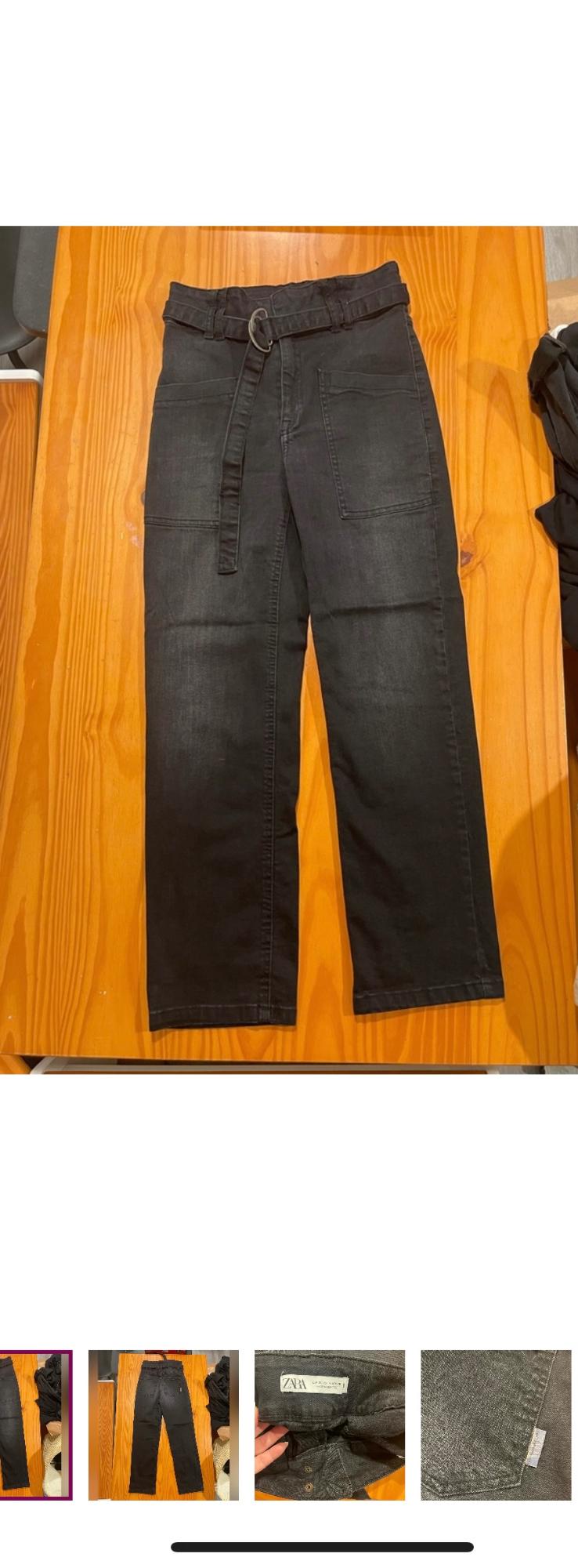 Front view of black pants with a belt and front pockets.