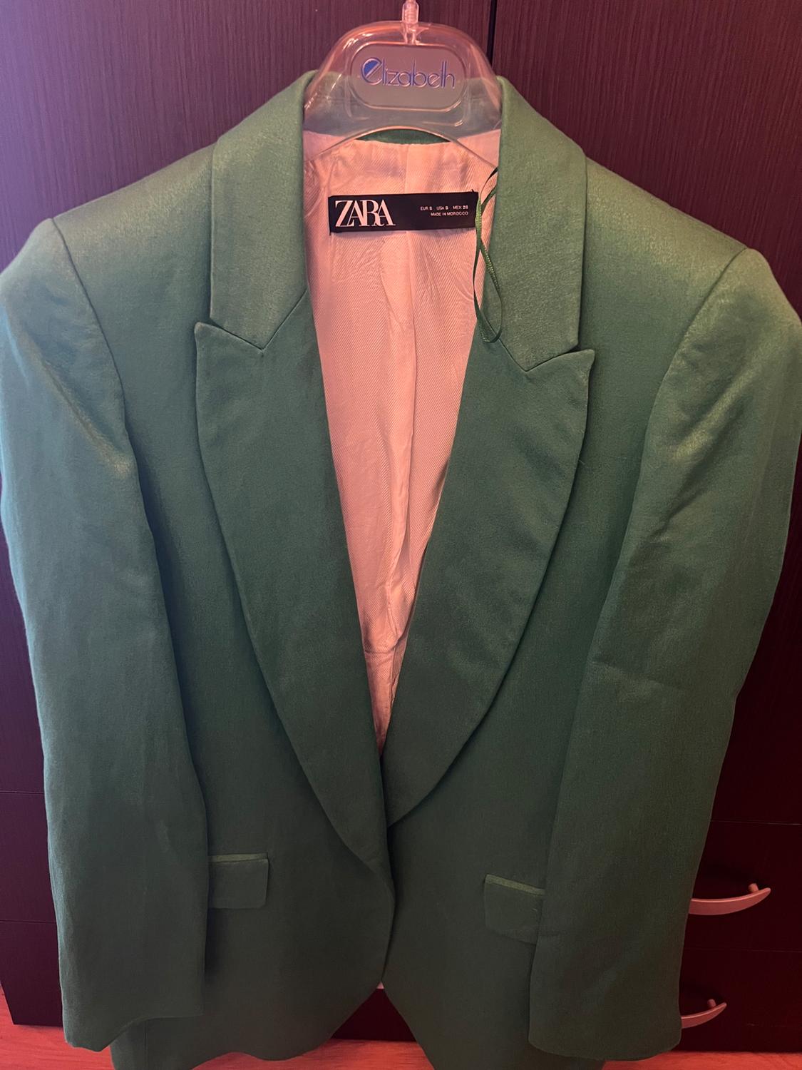 Front view of a green blazer with wide lapels and flap pockets.