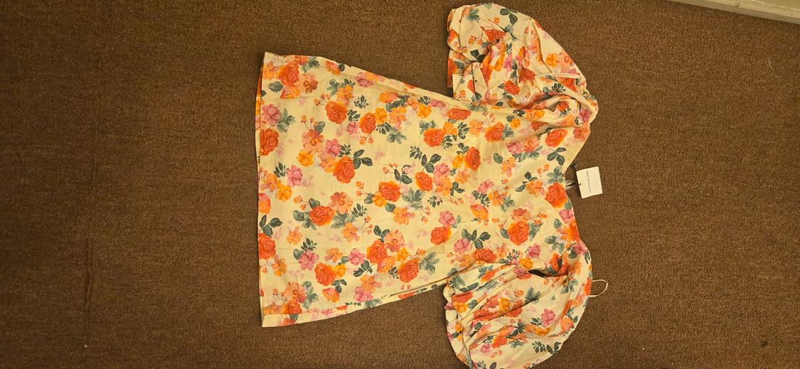 Front view of a floral print dress with puff sleeves in shades of orange, pink, and green.
