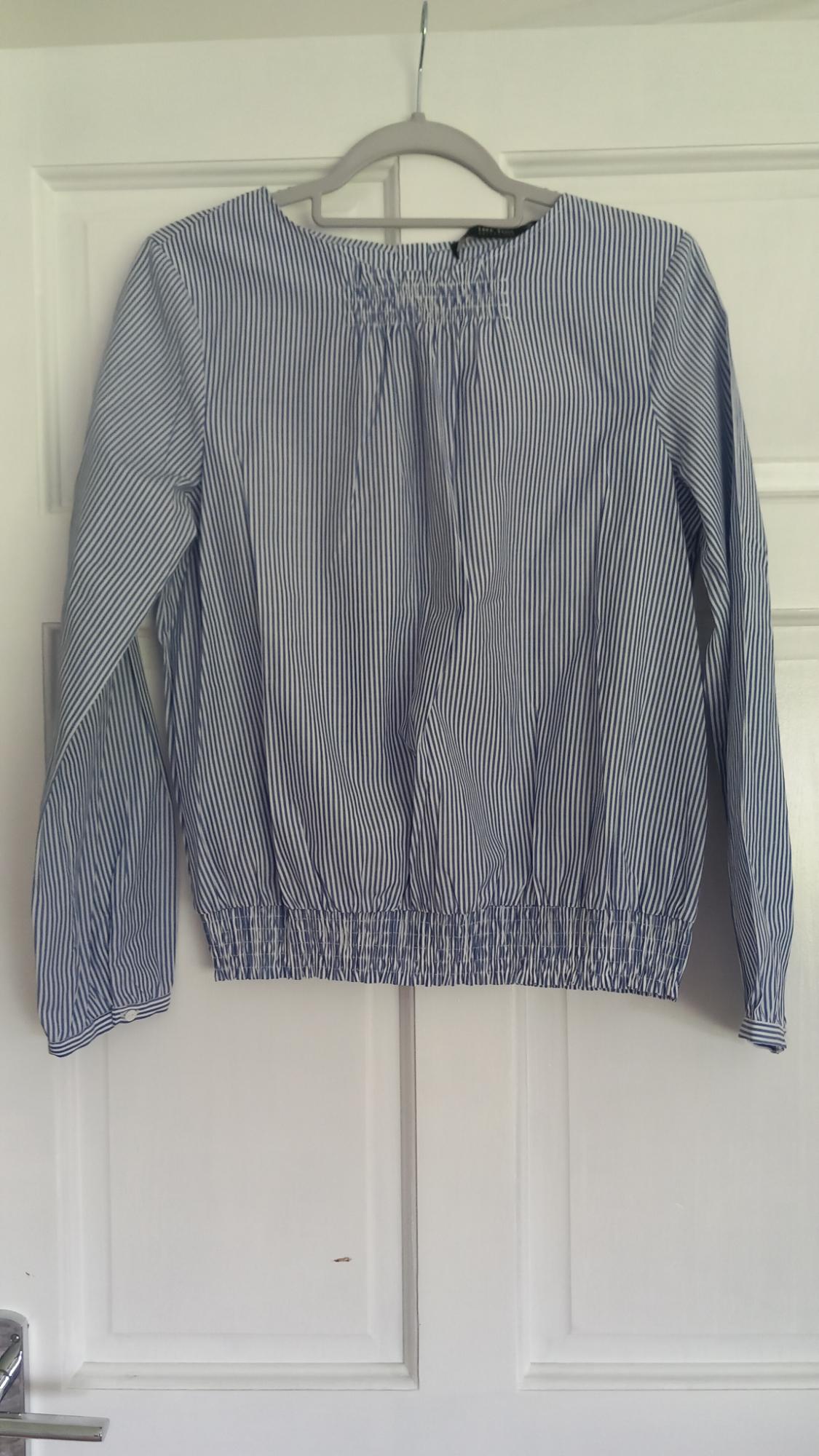 Front view of a blue and white striped blouse with long sleeves and elastic at the neck and waist.