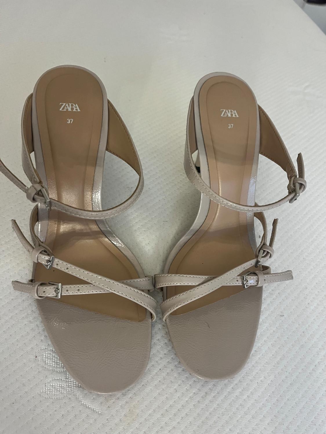 Front view of beige sandals with criss-cross straps and buckles, 'ZARA 37' text on insole.