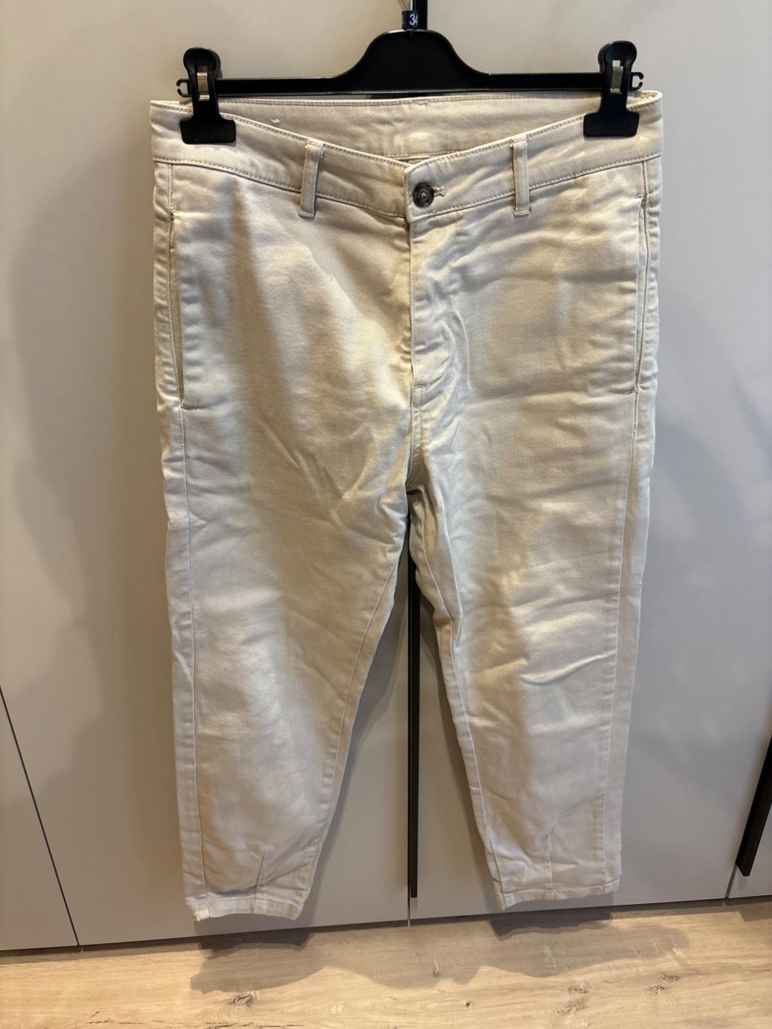 Beige trousers hanging on a black hanger against a light background. Size 34 is displayed on the hanger.