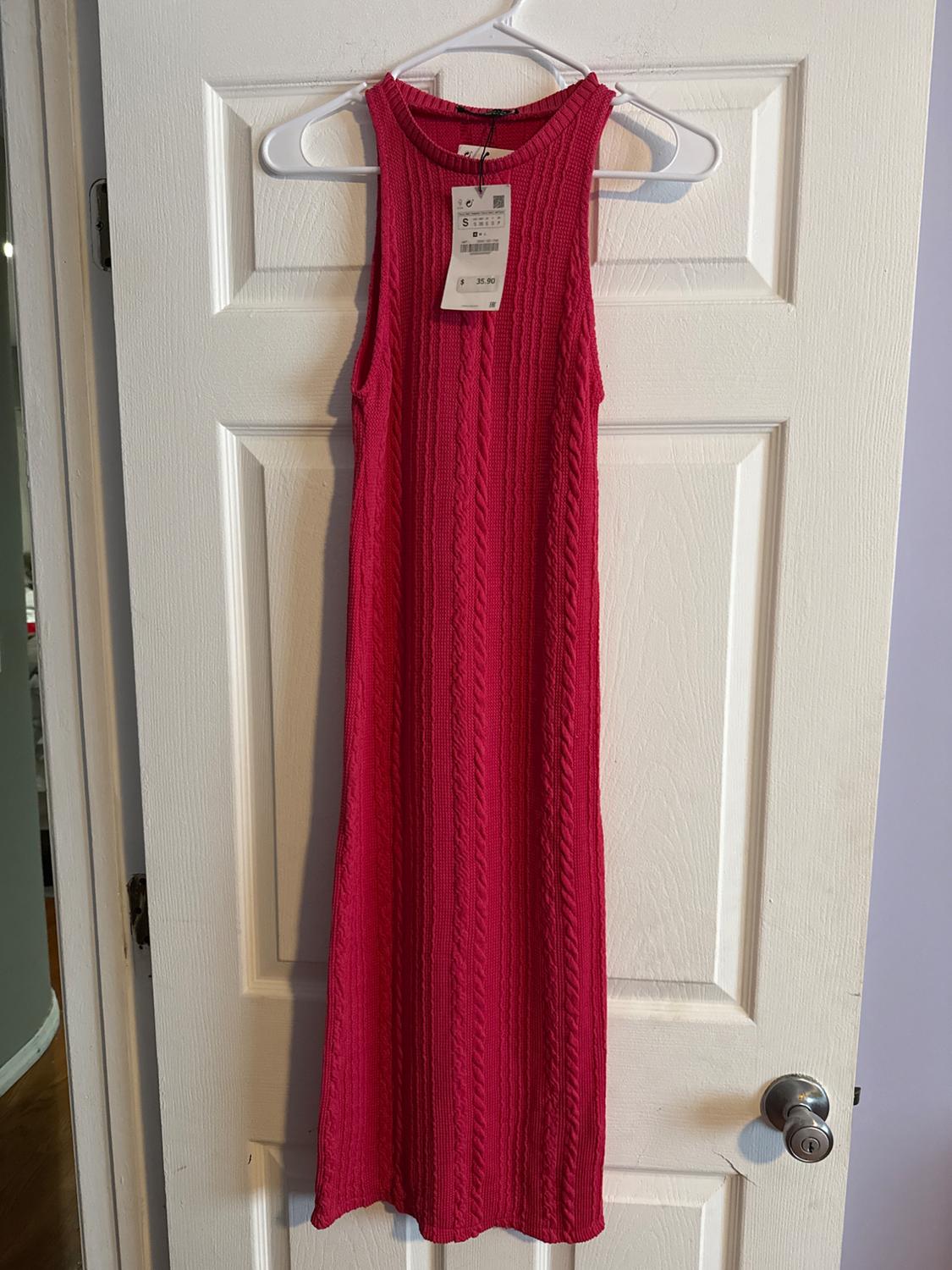 Red sleeveless dress hanging on a white hanger over a white door. Visible tag with price of $35.50.