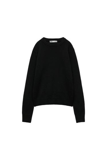 Black knit jumper with long sleeves and a round neck against a white background. Interior label with the text ZARA.
