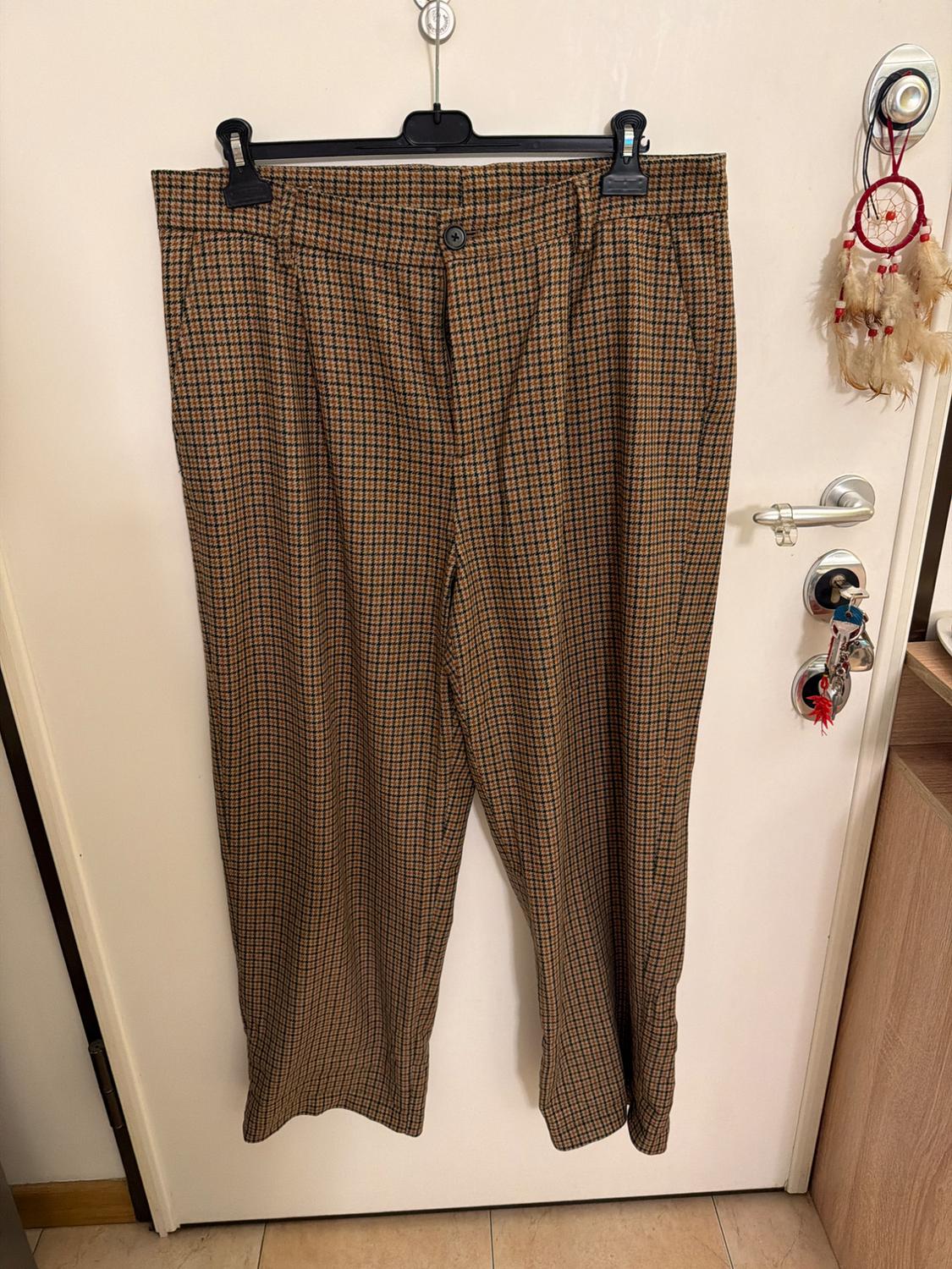 Brown checked trousers hanging on a white door. Relaxed, homely atmosphere, with a dreamcatcher and keys in the lock.