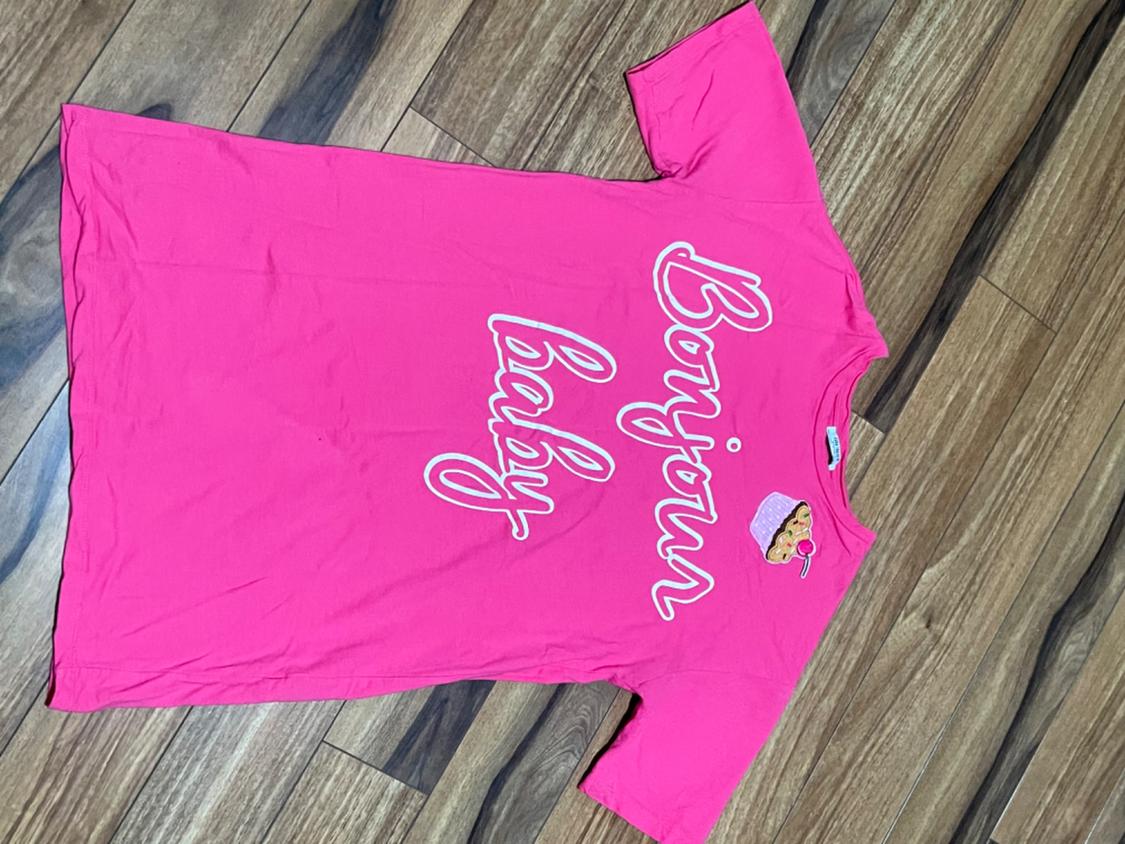 Front view of a pink t-shirt with 'Bonjour baby' text and a cake print on the chest.