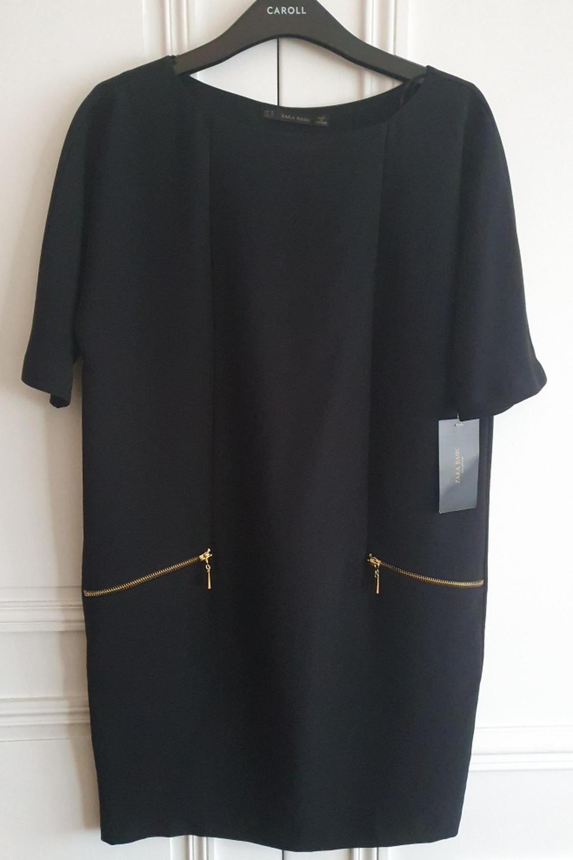 Front view of black dress with gold zips on side pockets