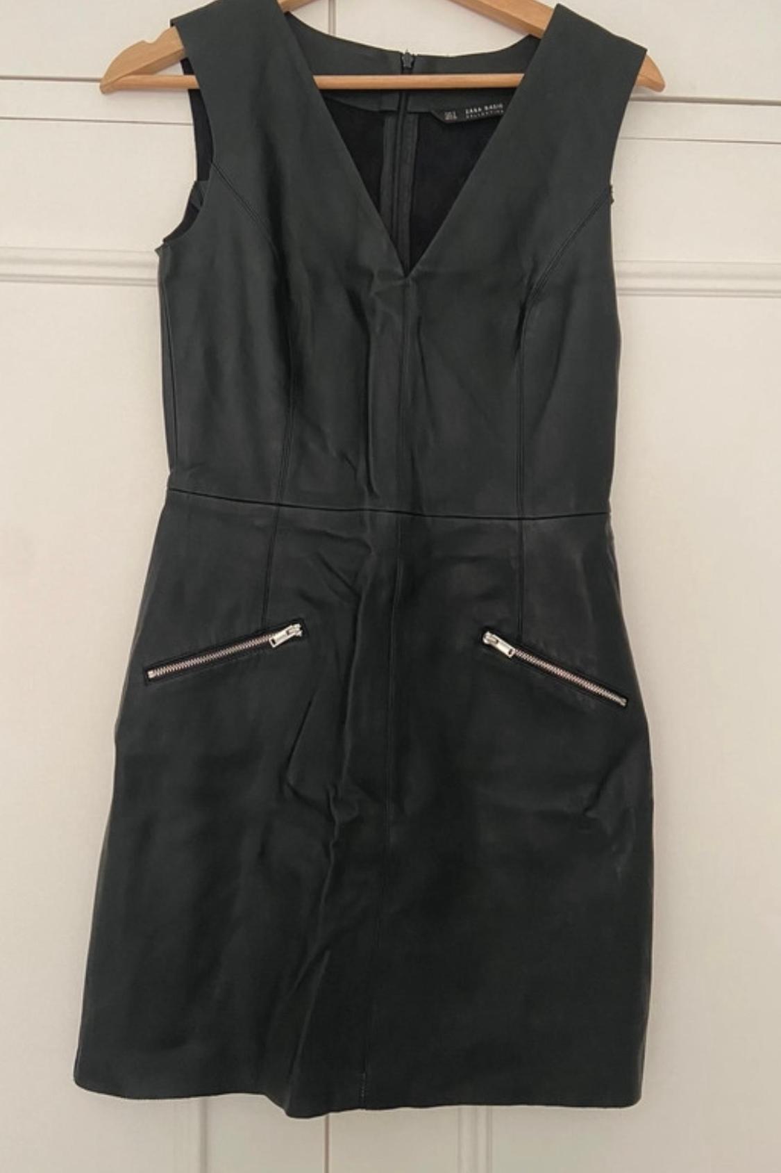 Front view of black sleeveless dress with V-neck and zip pockets.
