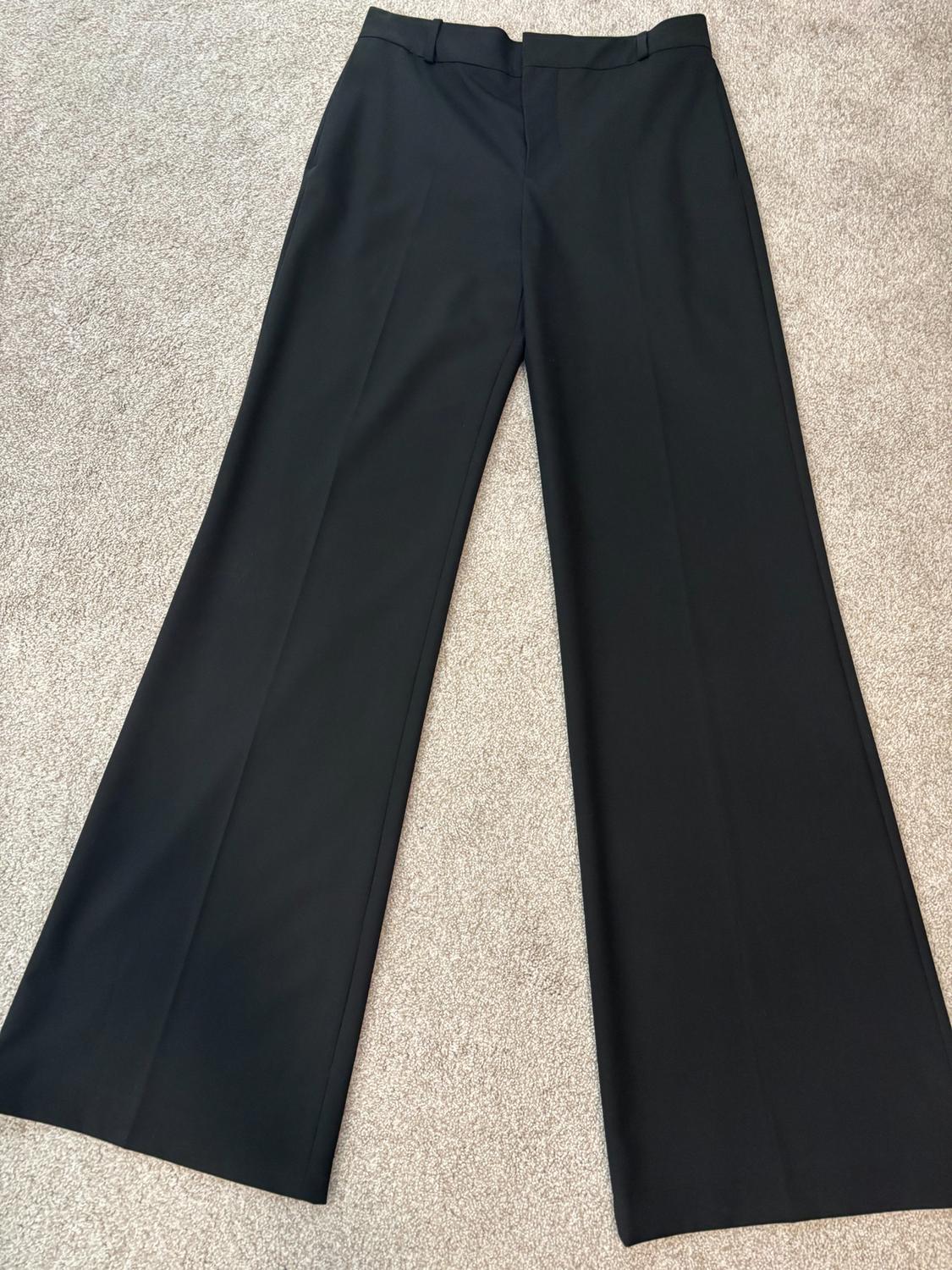 Black wide-leg pants on a beige rug, showcasing a classic and elegant design.