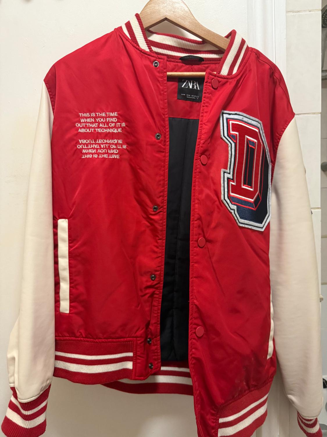 Varsity style jacket in red with white sleeves, "D" letter embroidery, text on the chest and stripe details on the collar, cuffs and hem.