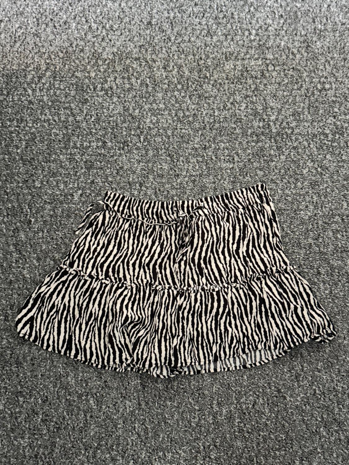 Short skirt with black and white animal print stripes on a grey textured background.