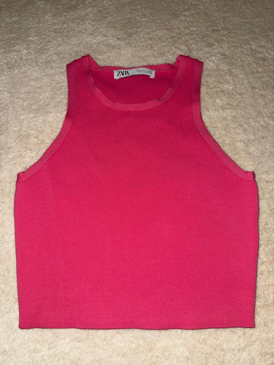 Hot pink sleeveless crop top on a beige surface. Visible label with text "ZARA".