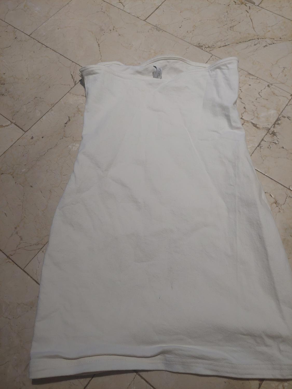 Basic white strapless dress laid out on a light-tiled floor. Casual and relaxed style.