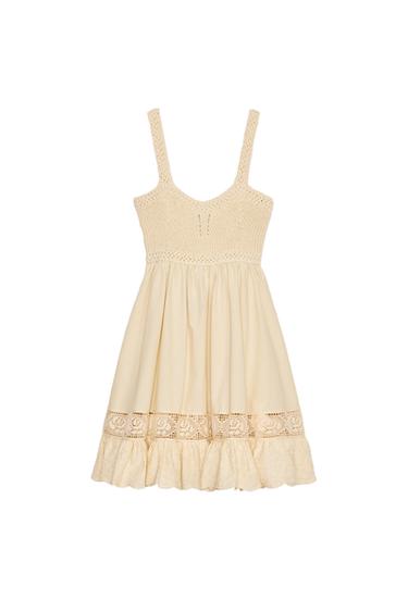Front view of beige dress with straps and lace detailing at the waist and hem.