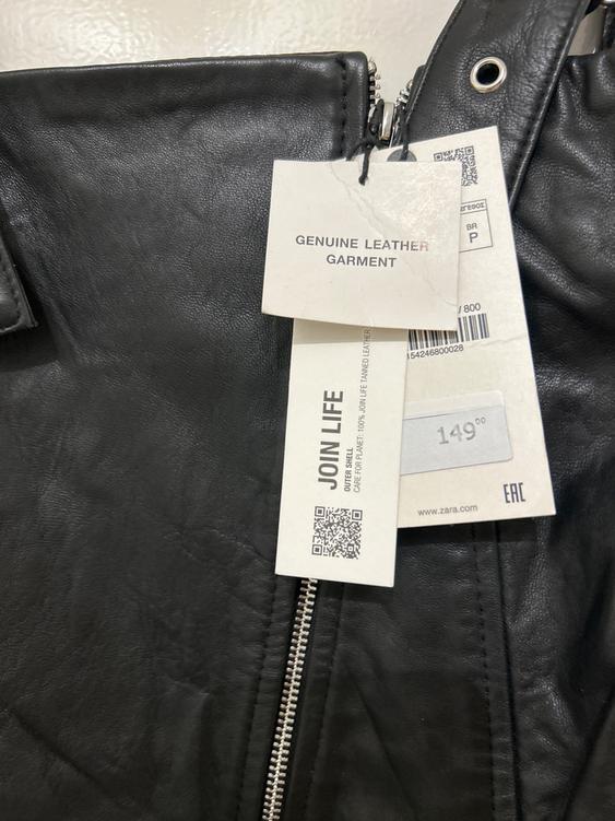 Genuine leather garment label with "JOIN LIFE" text and price of 149.00 on a black jacket with visible zip.