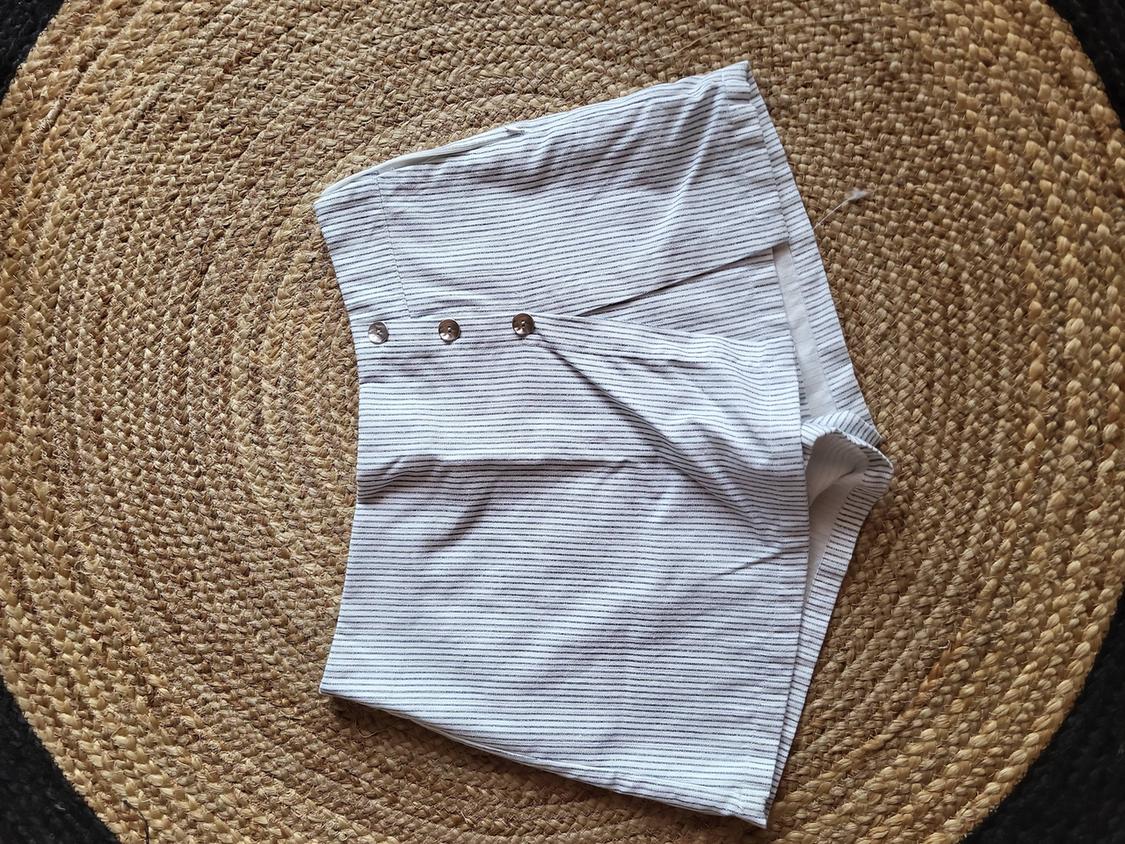 Black and white striped shorts with metal buttons, on a spiral braided jute rug.